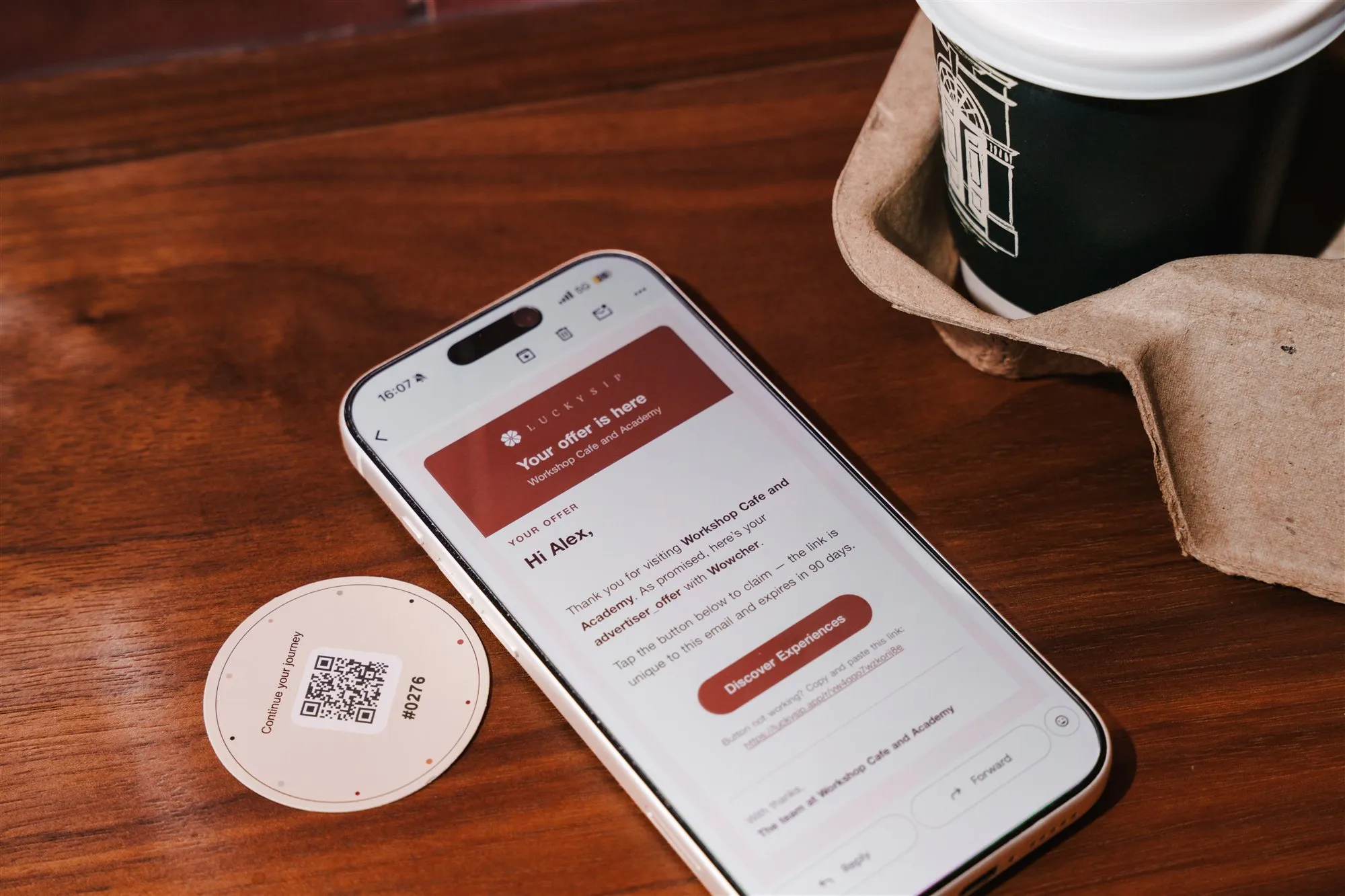A phone showing a LuckySip offer email beside a real printed QR and Card Code card.